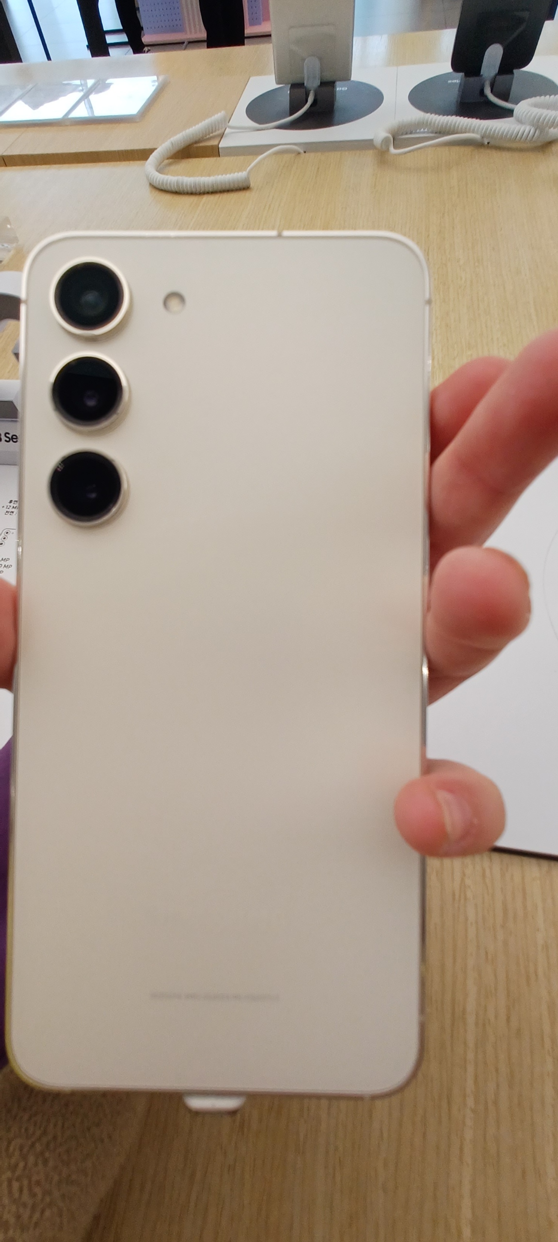手に持ったクリーム色のGalaxy S23の背面参考写真。紹介はSC-51D・256GB・ラベンダーで、出品個体ではありません。写真の地域型番は未確認。 写真：Questions and／CC BY-SA 4.0。独自加工なし。